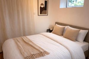 a bedroom with a bed with white sheets and a window at Santos in Noordwijk aan Zee