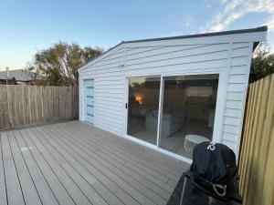 a small white shed with a bed in it at Private Barwon Heads Cottage Walk to River in Barwon Heads +2 photos