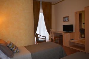 a hotel room with a bed and a desk with a television at La Collina Hotel & Spa in Oliveto Citra