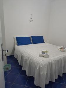 a white bed with blue pillows and shoes on it at Il nido dei nonni in Maiori