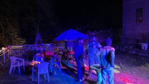 a group of men standing under an umbrella at night at Mahi camping & cottages in Jagatsukh