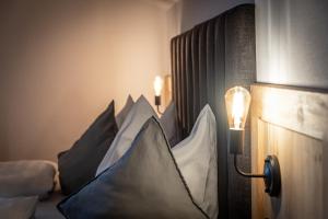 Eine Reihe Kissen auf einem Bett mit einer Lampe in der Unterkunft HAUSERHOF Farmhouse with Dolomite View in Villanders