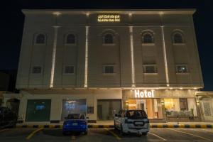 Aurion Al-Aqeeq Hotel في المدينة المنورة: فندق مع سيارتين متوقفتين أمامه