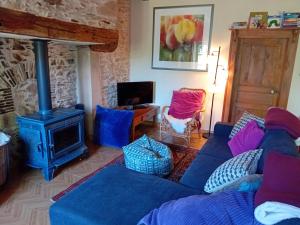 a living room with a blue couch and a stove at Petite Perle Parinet in La Croisille-sur-Briance