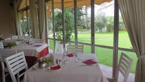a dining room with white tables and chairs and a large window at La Quiete Park Hotel in Manerba del Garda
