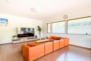 a living room with an orange couch and a tv at Links Seaside resort in Futtsu