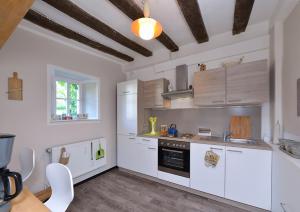een keuken met witte apparatuur en houten plafonds bij Zum Pinken Schaf in Ahrdorf