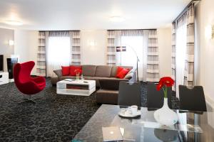 a living room with a couch and a red chair at Parkhotel Plzen Congress Center in Plzeň