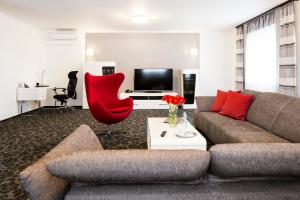 a living room with a couch and a red chair at Parkhotel Plzen Congress Center in Plzeň