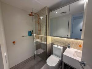 a bathroom with a toilet and a sink and a shower at Salt & Stone - Harbour Views, Balcony & Parking x1 in Newcastle +55 photos