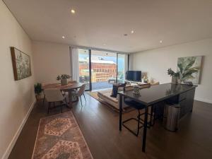 a living room with a table and a dining room at Salt & Stone - Harbour Views, Balcony & Parking x1 in Newcastle