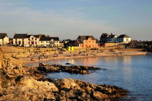 a group of people on a beach with houses at La Maison du Carbonet in Batz-sur-Mer