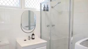 a bathroom with a shower and a sink and a mirror at Stylish Coastal Stay in Cronulla +12 photos