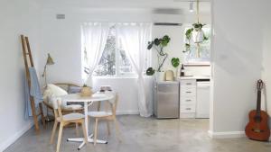 a kitchen with a white table and a kitchen with a guitar at Stylish Coastal Stay in Cronulla