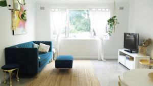 a living room with a blue couch and a tv at Stylish Coastal Stay in Cronulla