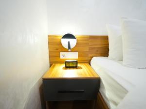 a bed with a night stand with a clock on it at Premiere Hotel Tashkent Pool&Spa in Tashkent