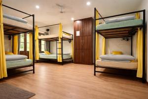 ein Zimmer mit drei Etagenbetten und gelben Vorhängen in der Unterkunft John's Homestay Srinagar - Stay Ride Hike in Srinagar