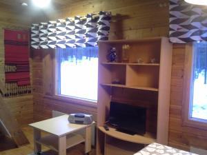 een woonkamer met een tv, een bureau en een tafel bij Vipati Cottage in Ylitornio