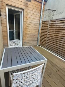 a wooden deck with a table and a bench at La maison de toujours in La Garenne-Colombes