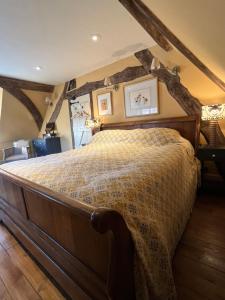 a bedroom with a large bed with wooden beams at Under The Thatch at Rose House in Iwerne Minster