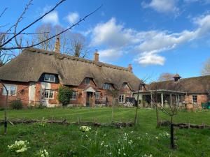 an old brick house with a thatched roof at Under The Thatch at Rose House in Iwerne Minster
