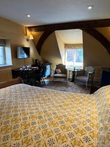 a bedroom with a bed and chairs and a desk at Under The Thatch at Rose House in Iwerne Minster