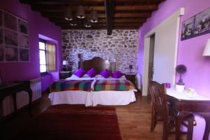 Dormitorio púrpura con cama y mesa en Os Tres Teixos en San Acisclo