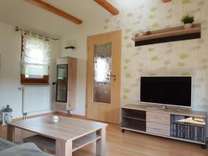 ein Wohnzimmer mit einem Flachbild-TV und einem Tisch in der Unterkunft Haus Talsperreneck in Stützengrün