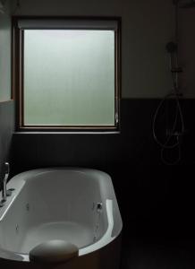 a bath tub in a bathroom with a window at BaanTataChiangmai in Ban Pong Khai Tai