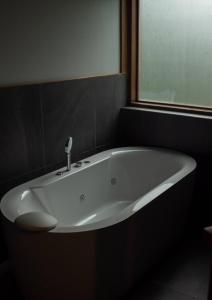 a white bath tub in a bathroom with a window at BaanTataChiangmai in Ban Pong Khai Tai