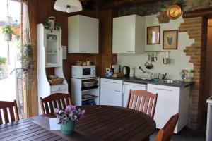 a kitchen with white cabinets and a wooden table at Ca' Merla affittacamere in Morbegno