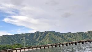 a bridge over the water with mountains in the background at LA Komodo Homestay in Komodo