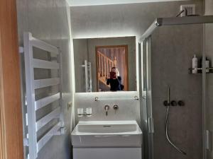 a person taking a picture of a bathroom with a sink at Jūrena in Nida +21 photos