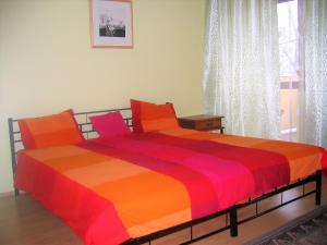 ein Schlafzimmer mit einem Bett mit einer orangen und roten Decke in der Unterkunft Aqua Apartman in Révfülöp