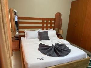 a bed with two black bow pillows on it at Spark Africa Hotel in Jinja