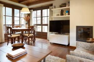 un soggiorno con TV e tavolo con sedie di Val de Ruda Luxe 6 by FeelFree Rentals a Baqueira-Beret