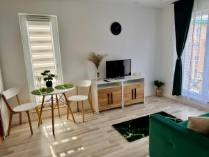 ein Wohnzimmer mit Fernseher, Tisch und Stühlen in der Unterkunft SunSet Studio by Cosmopolis in Ştefăneştii de Sus