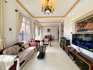 a living room with a couch and a tv at Tuong Vy Private Villa in Da Lat