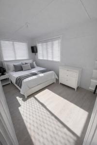 a white bedroom with a bed and two windows at North Hamptons Retreat in Bundaberg +5 photos