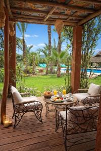 a patio with a table and chairs on a deck at Jnan Lotf Marrakech - Le Jardin de la Bienveillance in Marrakesh