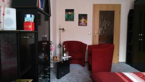 uma sala de estar com duas cadeiras vermelhas e uma cama em Ferienwohnung Anna em Greiz