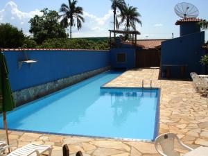 einem blauen Pool mit Stühlen und einer blauen Wand in der Unterkunft Pousada Rosa dos Ventos in Delfinópolis