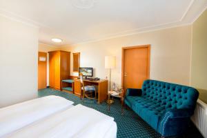 a hotel room with a bed and a blue couch at Hotel Kronprinz in Greifswald