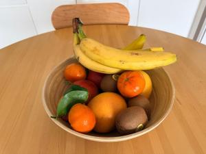 a bowl of fruit with bananas and oranges on a table at Chambre chez l habitant terrasse vue mer in Sainte-Maxime