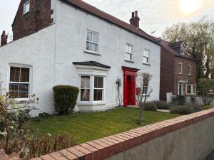 a white house with a red door at Pinfold House in Wistow