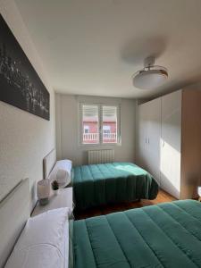 a bedroom with two green beds and a window at Las Candelas, Casa Turística in Uruñuela