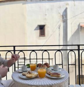 ein Tisch mit Tellern voller Essen und zwei Bechern Orangensaft in der Unterkunft Eldoh in Bernalda + 11 Fotos