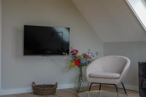 a living room with a chair and a vase with flowers at Landgoed Erve Triesthaar in De Lutte