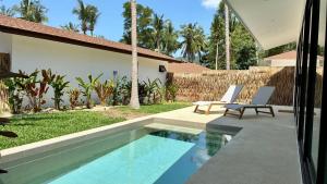 a swimming pool in a yard with two chairs and a house at Samma Villas - Onyx Villa - 1 BDR & Private Pool in Ko Phangan