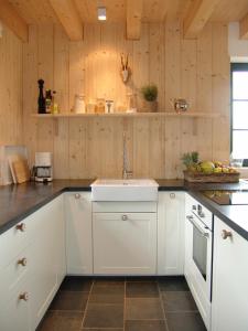 cocina con fregadero blanco y paredes de madera en Ferienhaus am Nationalpark en Morsbach